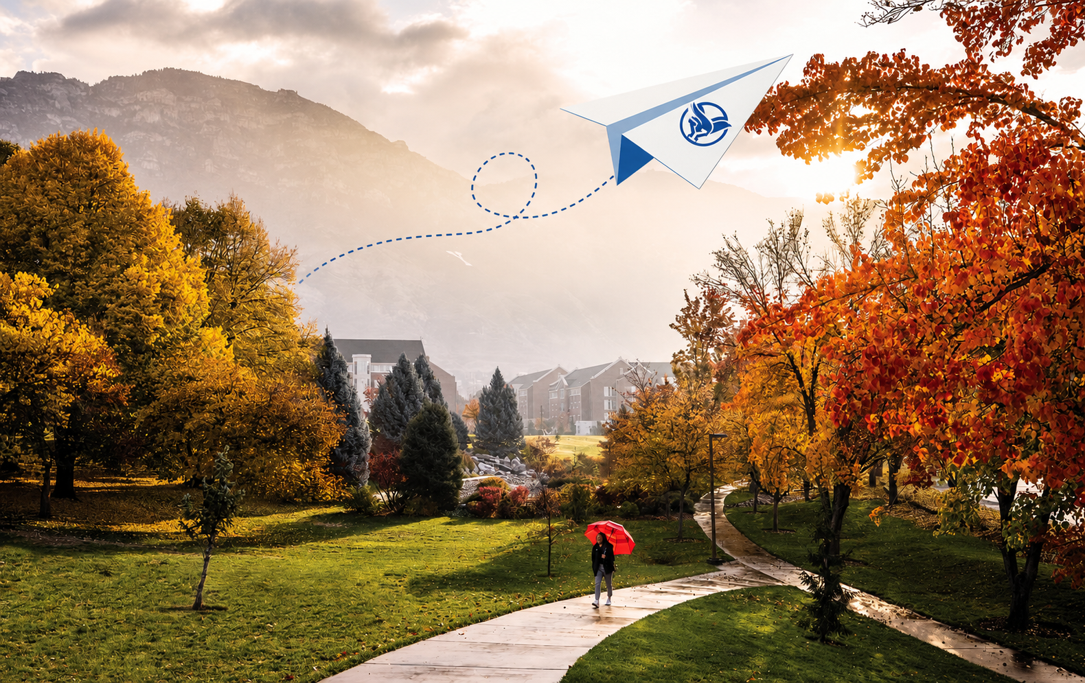 A student walking across the BYU campus in autumn beneath a BirdsEye paper airplane