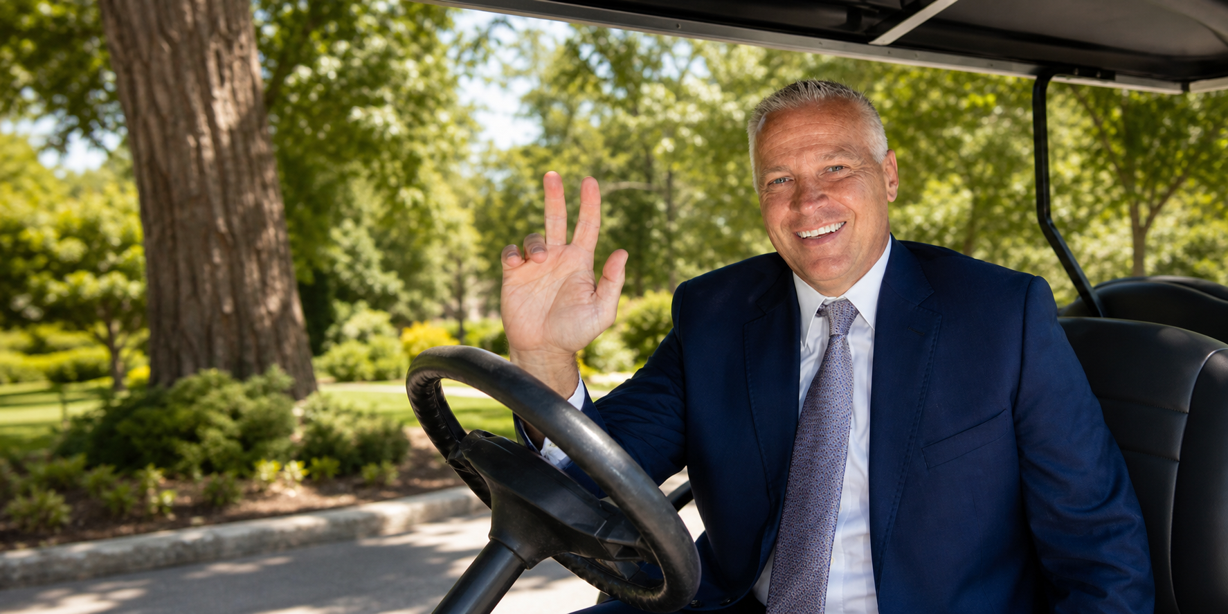 BYU President Shane Reese smiling and waving from a golf cart